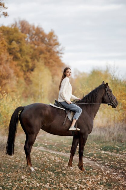 Una niña con un caballo en la naturaleza, un paseo otoñal con un animal.