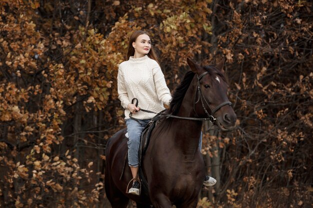 Una niña con un caballo en la naturaleza, un paseo otoñal con un animal.