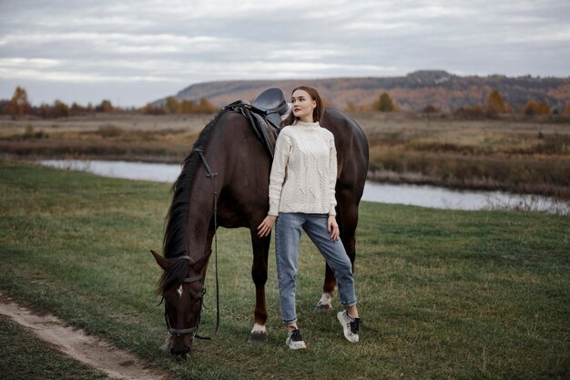 Una niña con un caballo en la naturaleza, un paseo otoñal con un animal.