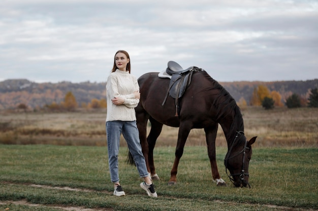 Una niña con un caballo en la naturaleza, un paseo otoñal con un animal.