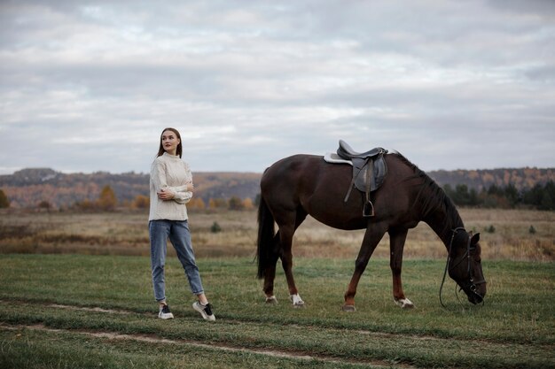 Una niña con un caballo en la naturaleza, un paseo otoñal con un animal.