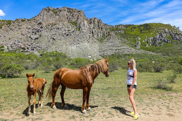 Una niña y caballos contra el fondo de antiguas montañas altas en una neblina de aire Demerji Crimea