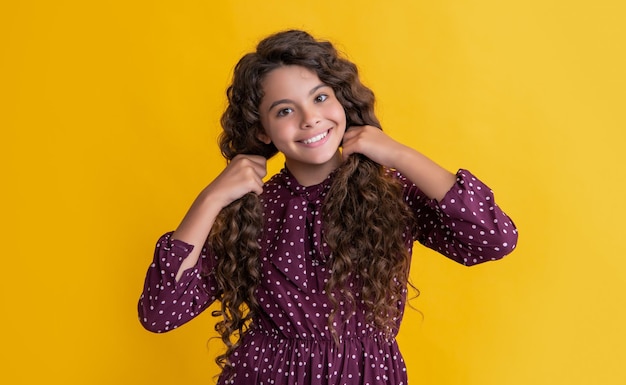 Niña con cabello largo y rizado morena sobre fondo amarillo