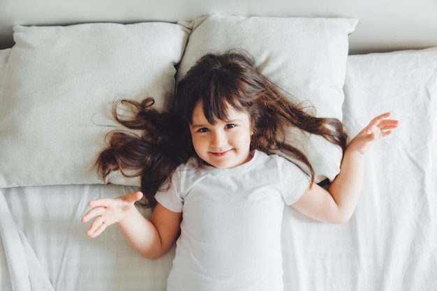 Una niña de cabello oscuro está durmiendo en la cama, un niño está acostado en la vista de la cama desde arriba para recibir mensajes de texto