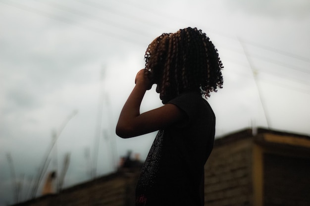 Niña con el cabello rizado de pie contra el cielo