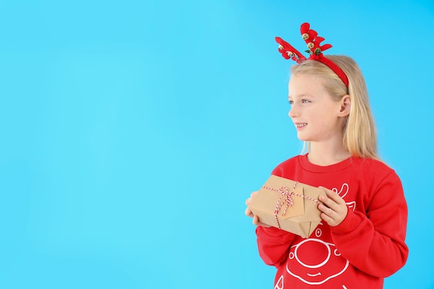 Niña con caja de Navidad sobre fondo azul.