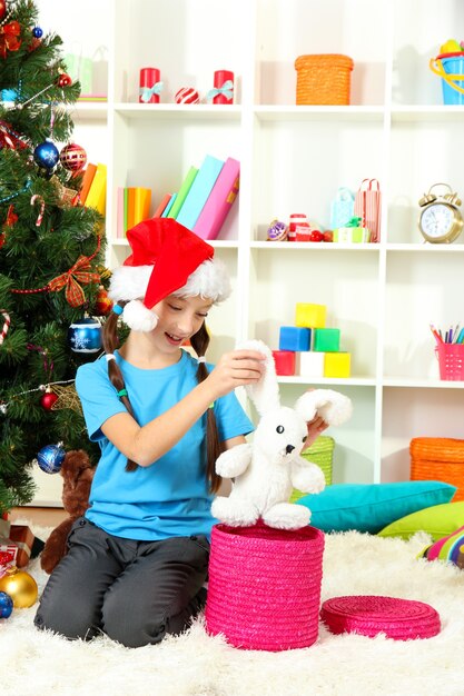 Niña con caja presente cerca del árbol de navidad