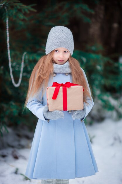 Niña con caja de regalo de navidad en invierno al aire libre