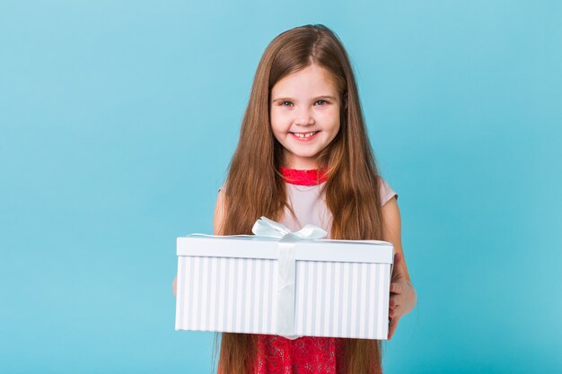 Niña con caja de regalo sobre fondo azul.