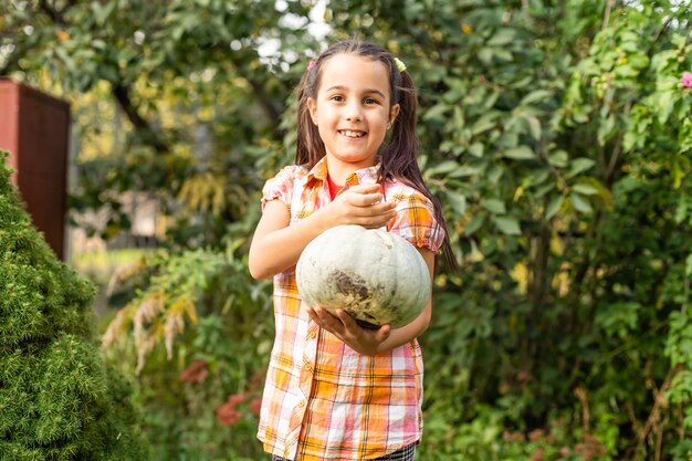 Niña con una calabaza en el jardín