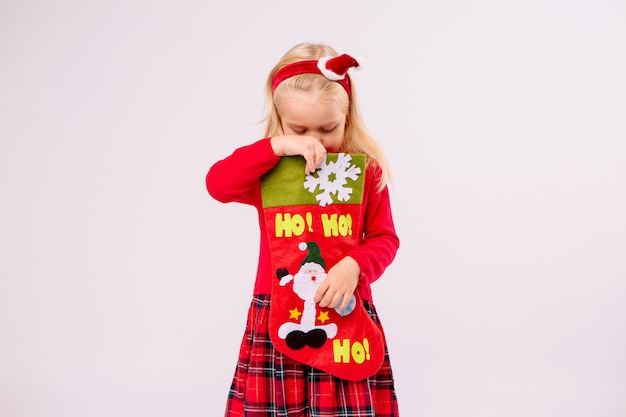 Niña con calcetín de Navidad para regalos en la pared blanca