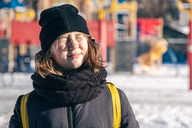 Una niña se calienta al sol en un clima frío de invierno