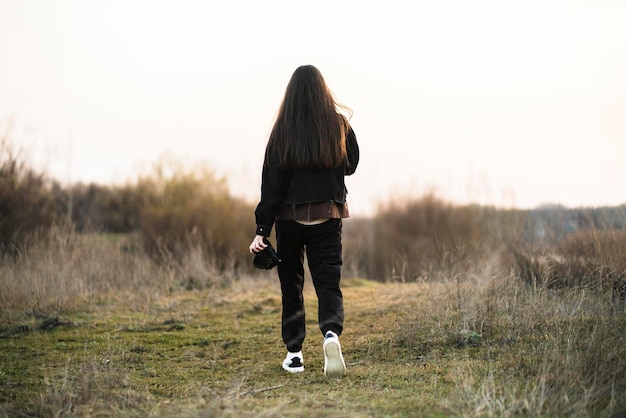 Una niña camina al aire libre en la escena de la naturaleza al atardecer o al atardecer vista desde atrás