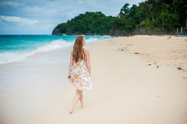 La niña camina al borde del agua en el Boracay