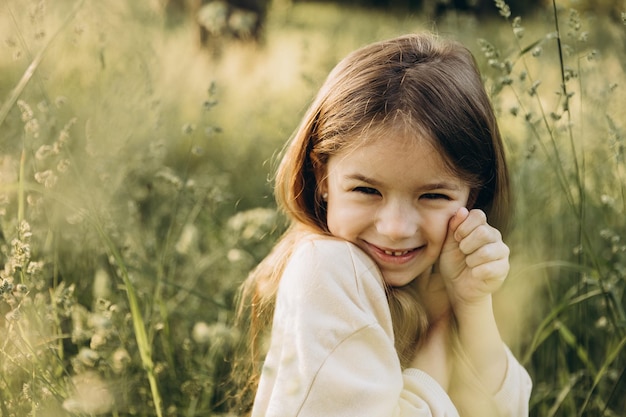 Una niña camina en un bosque de coníferas entre hierba alta antes del atardecer