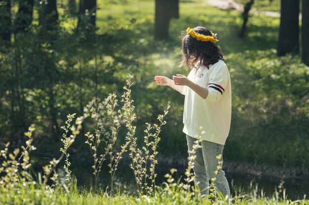 Una niña camina por el bosque con una corona de dientes de león.