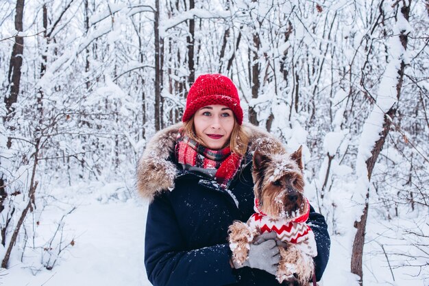 Niña camina en el bosque inferior en invierno con perro vistiendo un suéter de navidad