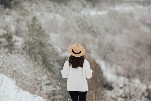 Niña camina en el bosque nevado de invierno. Vista trasera.