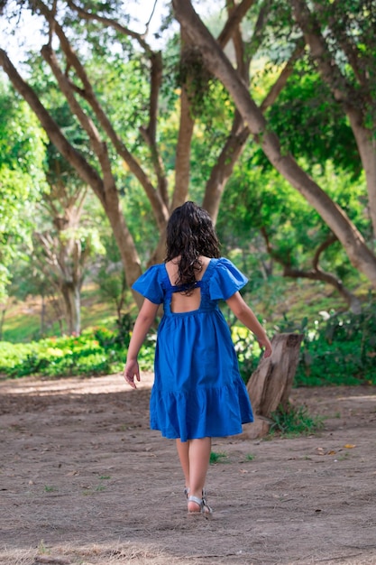 Una niña camina por un bosque, con un vestido azul.