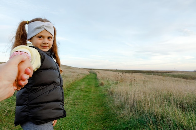 Foto una niña camina por un camino de la mano de un chico.