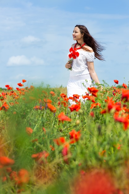 Niña camina en un campo de amapolas