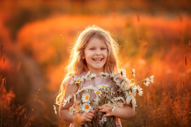 Foto una niña camina en un campo con margaritas.