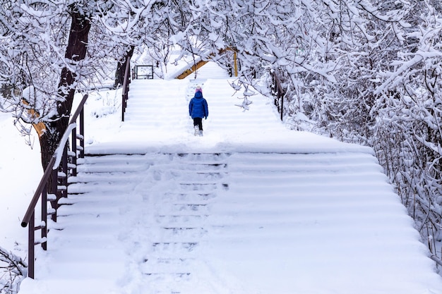 Una niña camina por una escalera cubierta de nieve en un día de invierno