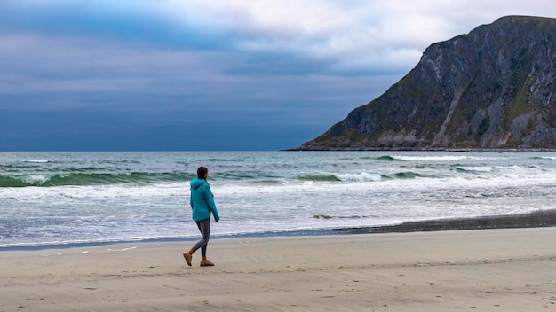 una niña camina en la famosa playa de los surfistas - playa de uttakleiv en las islas lofoten de noruega