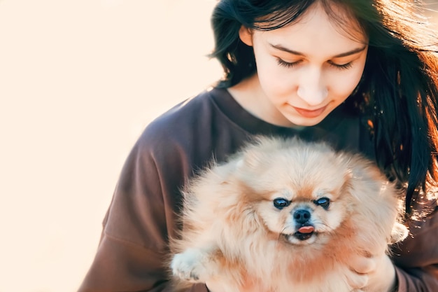 Una niña camina con un perro en la recreación al aire libre del parque con una mascota un retrato con un cachorro pequeño