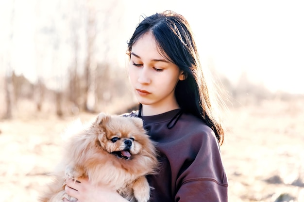 Una niña camina con un perro en la recreación al aire libre del parque con una mascota un retrato con un cachorro pequeño