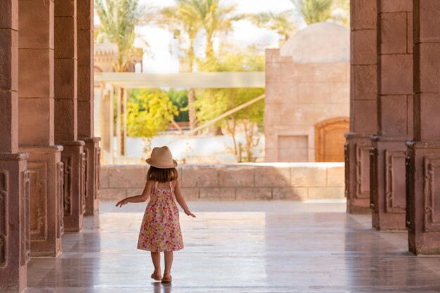 Una niña camina por el pórtico entre las columnas en egipto