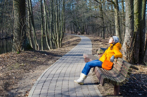 Niña camina en la primavera en la chaqueta naranja y bolso naranja