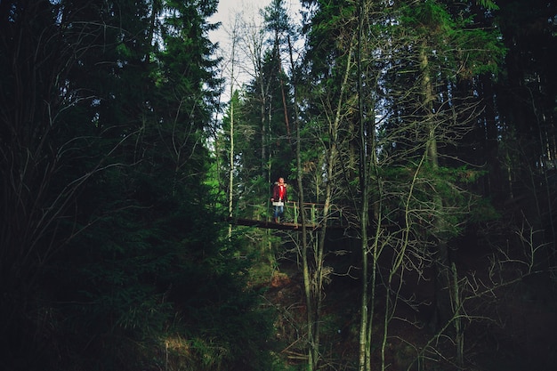 La niña camina sobre un puente colgante sobre un río de montaña. Bosque oscuro y místico.