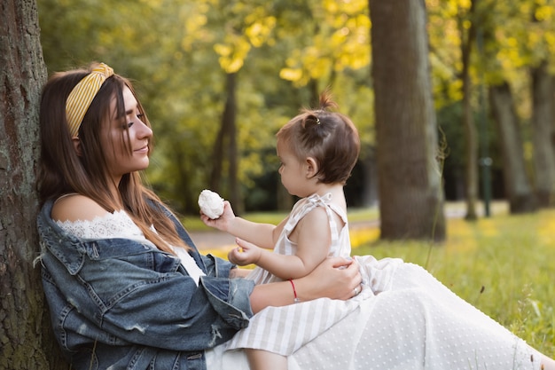 Una niña camina con su madre al aire libre.