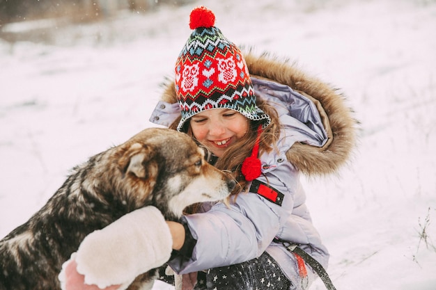 Una niña camina con su perro en el bosque de invierno.