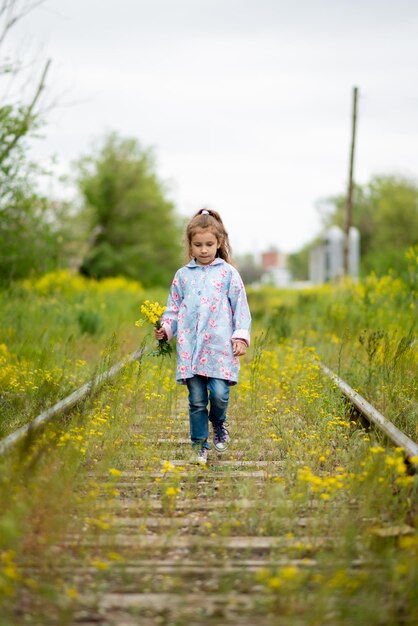 Una niña camina por las vías del tren cubiertas de hierba Ecología