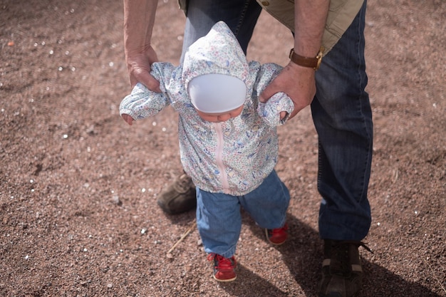 Niña caminando al aire libre con el hombre Abuelo ayudando a su nieta a caminar