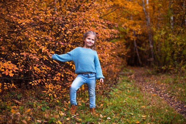 niña caminando en el bosque de otoño con ropa azul
