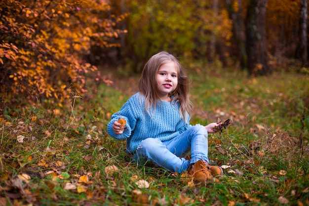 niña caminando en el bosque de otoño con ropa azul