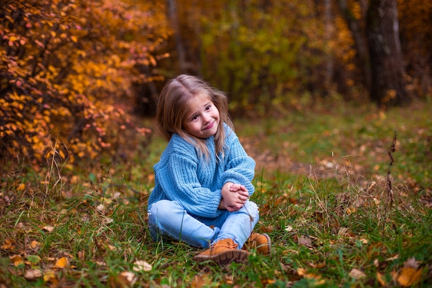 niña caminando en el bosque de otoño con ropa azul