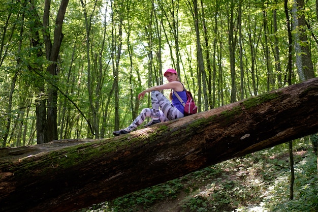 Niña caminando en el bosque, subiendo al tronco