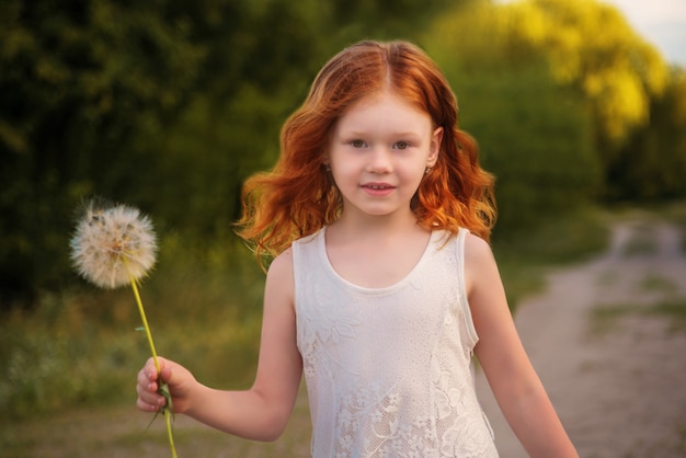 niña caminando con diente de león en verano