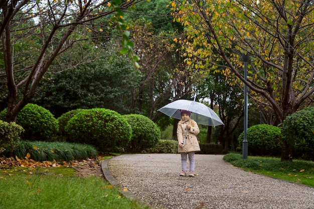 Niña caminando en un parque bajo un paraguas durante una lluvia