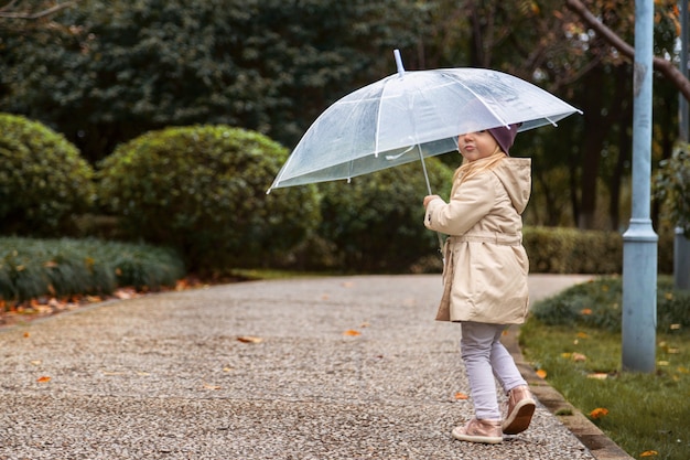 Niña caminando en un parque bajo un paraguas durante una lluvia