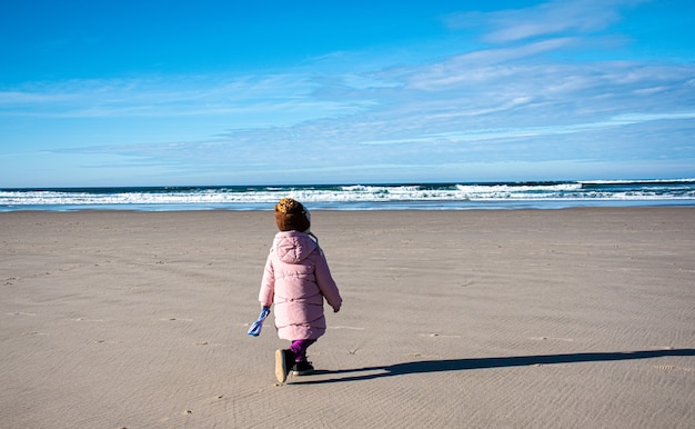 niña caminando por la playa en invierno