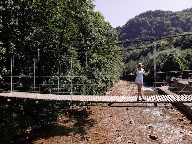 La Niña caminando por el puente y disfrutando del turismo a través del bosque.