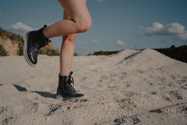 Foto niña caminando sobre la arena. botas y piernas