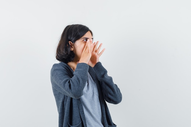 Niña en camiseta, chaqueta gritando o anunciando algo, vista frontal.