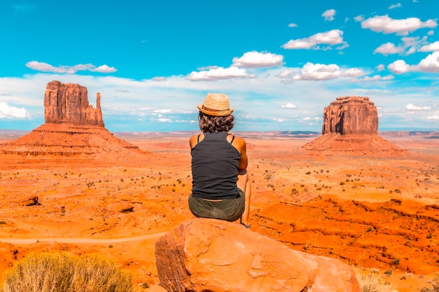 Una niña con camiseta negra sentada en el centro de la foto sobre una piedra en el Parque Nacional Monument Valley