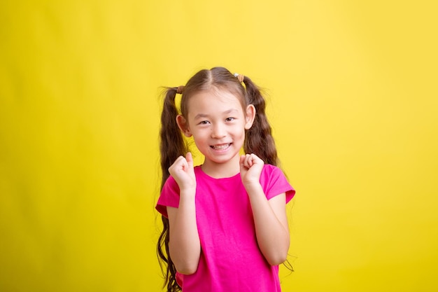 Una niña con una camiseta rosa está feliz con un fondo amarillo